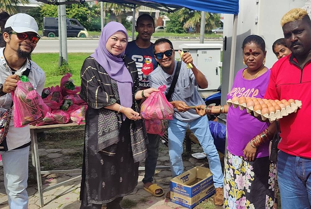 Nurul Syazwani (dua dari kiri) menyampaikan barangan basah kepada penerima pada Majlis Sumbangan Deepavali di pekarangan PKM DUN Permatang, Jalan Peninsula Utama, di sini pada Sabtu.
