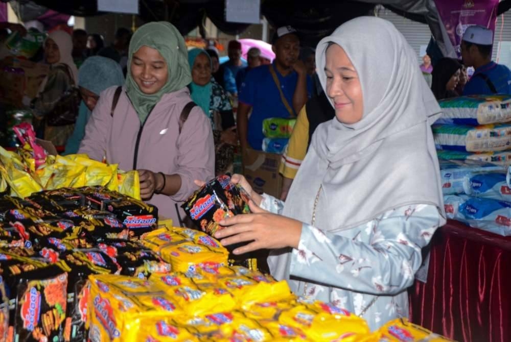 Orang ramai tidak melepaskan peluang mendapatkan barangan keperluan harian pada Program Jualan Rahmah di Dataran Durian Kampung Jelatok hari ini. - Foto Bernama