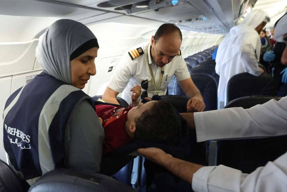 Sukarelawan mengangkat seorang kanak-kanak Palestin yang cedera keluar dari pesawat sebaik tiba di Abu Dhabi pada Sabtu. - Foto: AFP