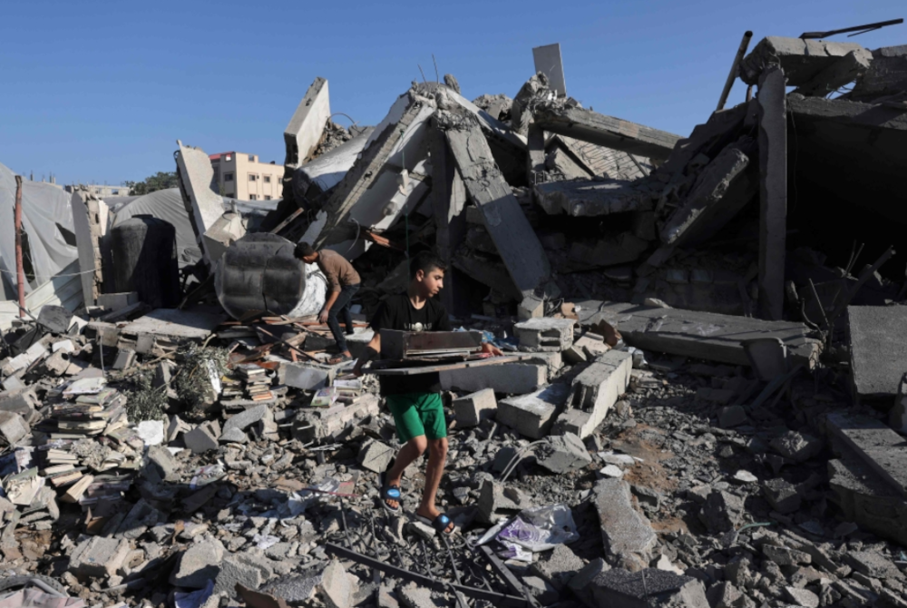 -
Kanak- kanak Palestin mengumpulkan buku diambil di kediamannya yang musnah dibedil Israel. -Foto AFP