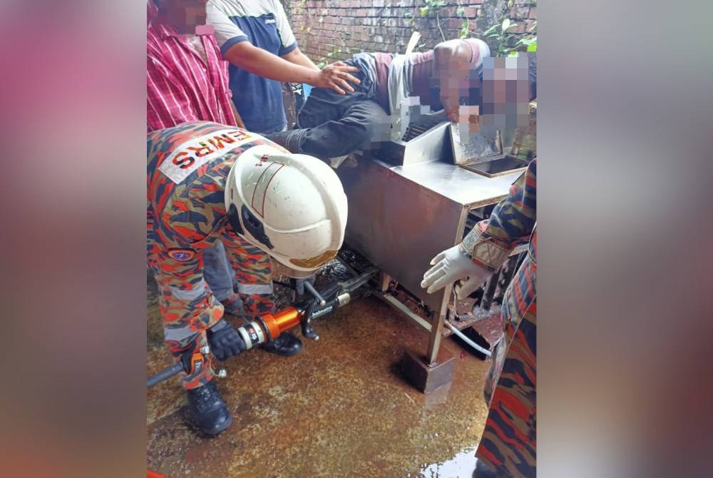 Anggota bomba menggunakan peralatan khas mengeluarkan tangan seorang lelaki yang tersepit dalam mesin memproses ayam.