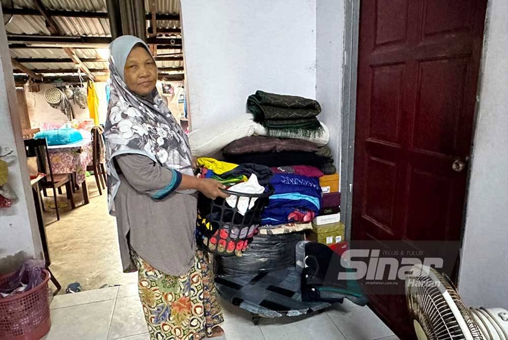 Mariam siap meletakkan pakaian ke tempat lebih tinggi bagi menggelak basah jika air masuk ke dalam rumah.