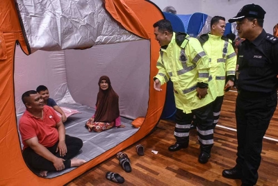 Mazli (tiga dari kanan) beramah mesra bersama mangsa banjir yang ditempatkan di PPS Dewan Serbaguna Tok Jembal selepas rumah mereka dinaiki air, pada Isnin. - Foto Bernama
