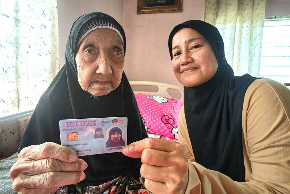Norazizah memegang kad pengenalan Uwan Lipah yang menunjukkan tarikh lahirnya.