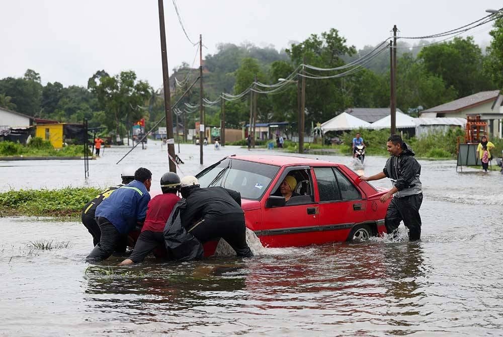 Sekumpulan lelaki membantu menolak kereta yang terbabas ke dalam longkang selepas jalan raya dilimpahi air ekoran hujan lebat sejak beberapa hari lepas semasa tinjauan di Kampung Alor Surau Panjang pada Selasa. - Foto Bernama