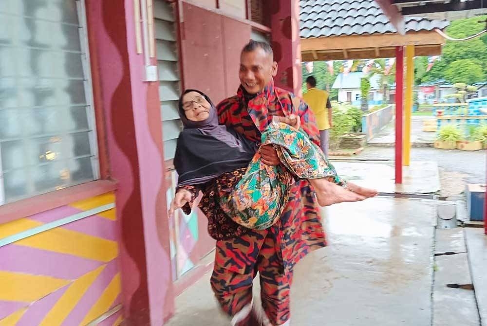Salah seorang anggota JBPM mendukung seorang warga emas uzur di Machang semasa sesi menyelamat mangsa banjir.