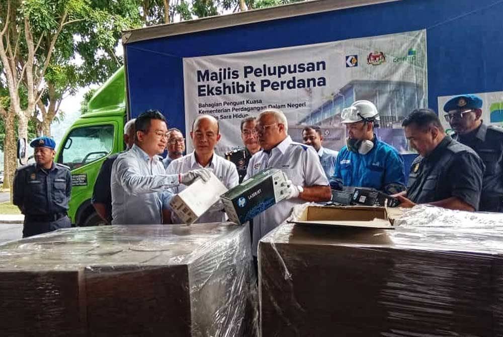 Mohd Sayuthi (lima kiri) ketika melihat dakwat mesin pencetak yang akan di lupuskan.