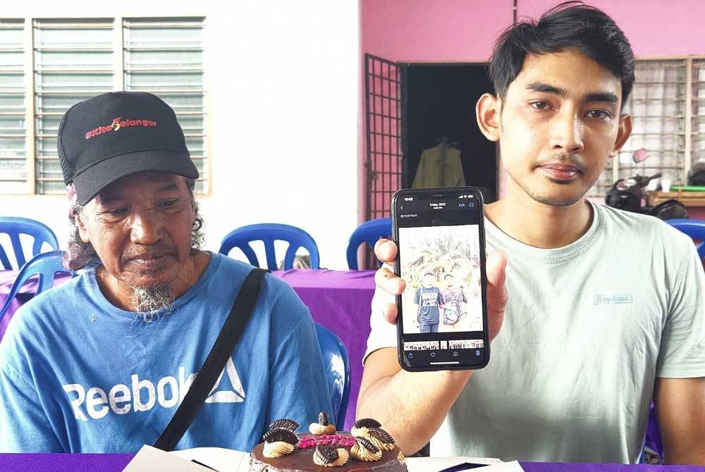 Muhammad Zulhemi (kanan) dan Shahrom (kiri) menunjukkan gambar arwah serta kek hari lahir itu di Kampung Bukit Kuching Tengah di sini pada Rabu.