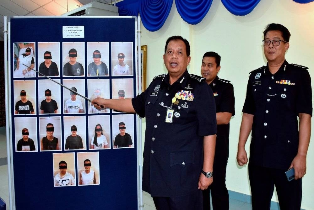 Zainol (kiri) menunjukkan gambar 17 suspek yang ditahan terlibat menjalankan operasi 'calling centre' di sebuah rumah banglo di Ayer Keroh. - Foto Bernama