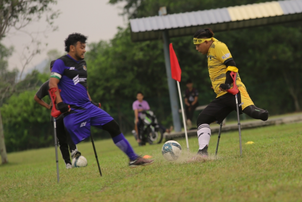 Aksi pemain bola sepak orang kudung pasukan kebangsaan (baju biru) merebut bola daripada pemain pasukan Perak pada perlawanan amal di Padang UniKL MIMET pada Rabu. - Foto Bernama