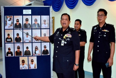 Zainol (kiri) menunjukkan gambar 17 suspek yang ditahan terlibat menjalankan operasi 'calling centre' di sebuah rumah banglo di Ayer Keroh. - Foto Bernama