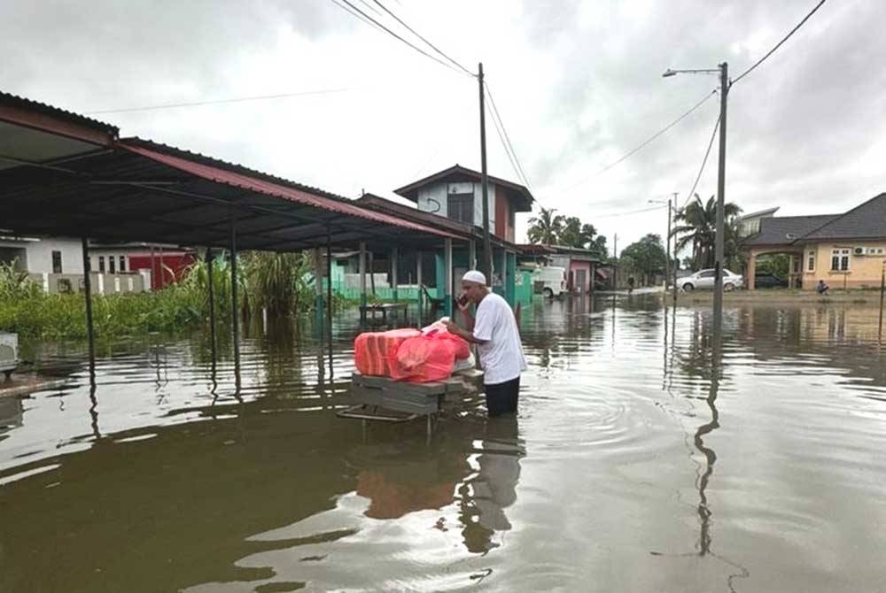 Shahmil Hameed memindahkan alatan pengurusan jenazah ke tempat lebih selamat setelah stor simpanan barangan itu di Kampung Nibong Atas di Kuala Terengganu dinaiki air pada Isnin lalu.