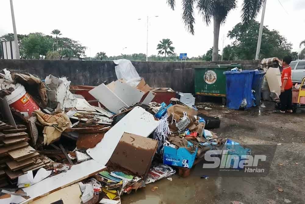 Mangsa banjir mengumpulkan barangan yang rosak termasuk perabot dan perkakasan rumah akibat ditenggelami air.