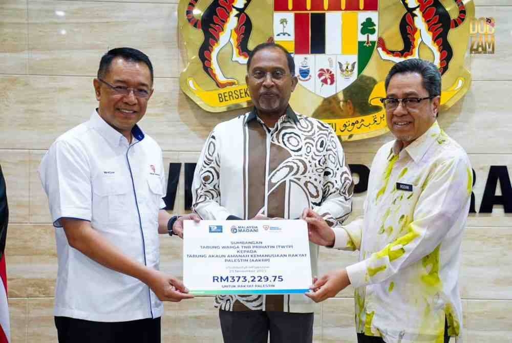 Zambry (tengah) menyaksikan penyerahan sumbangan daripada Wahizan (kiri) kepada Ahmad Rozian.