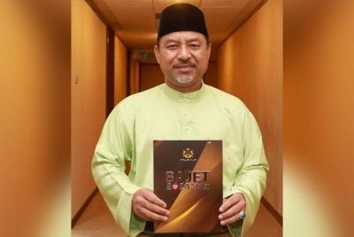 Mohd Nassaruddin menunjukkan fail Bajet Kelantan 2024 yang bertemakan 'Kelantan Mampan Berkat Sejahtera'.