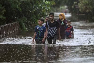 Penduduk meredah banjir untuk pulang ke rumah bagi melihat keadaan rumahnya selepas kawasan berkenaan dinaiki air ketika tinjauan di Kampung Gong Tok Nasek, Kuala Terengganu pada Rabu. - Foto Bernama