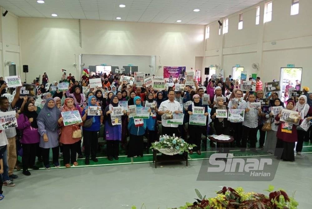 Suhaizan bersama penghuni PPR Melana Indah 2 menunjukkan plakad sebagai tanda sokongan kepada pembebasan rakyat Palestin di PPR Melana Indah 2, Johor Bahru, pada Sabtu.