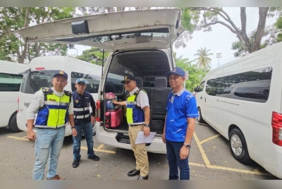 Lokman (dua dari kanan) bersama Roslan (kanan) menunjukkan van yang digunakan ulat pelancong untuk membawa penumpang dalam Ops Van Putih JPJ di Jalan Coastal, Kota Kinabalu.