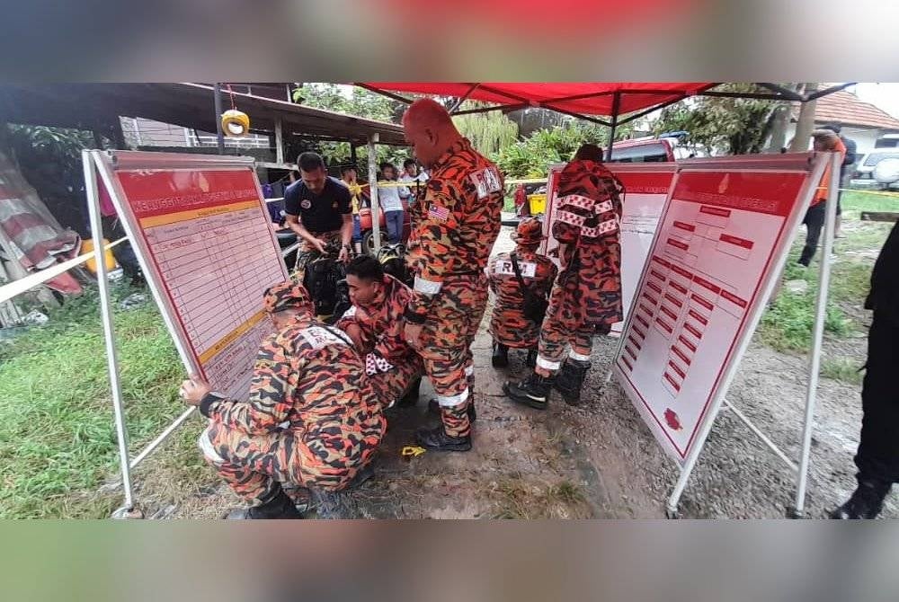 Anggota bomba melakukan pencarian mangsa yang tergelincir ke dalam sungai di belakang rumahnya di Kampung Kenari pada Ahad.