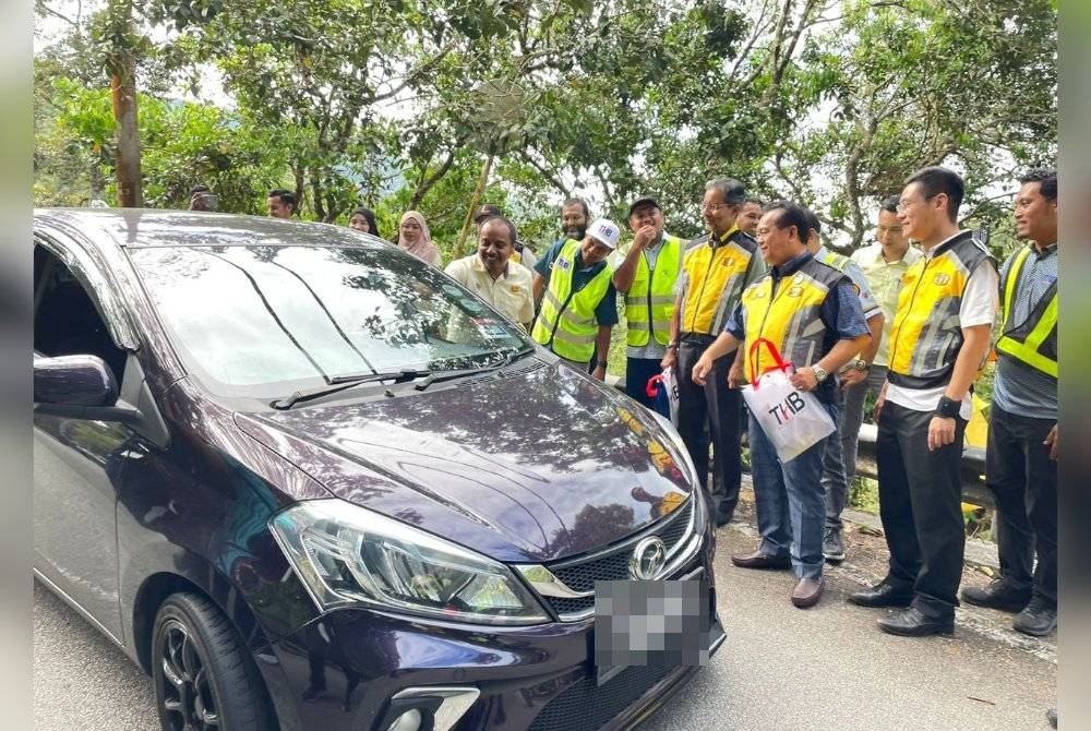 Alexander (tiga dari kanan) menyerahkan 'goodies bag' kepada pengguna jalan raya ketika meninjau hasil kerja pembaikan di Jalan Balik Pulau-Teluk Bahang pada Ahad.