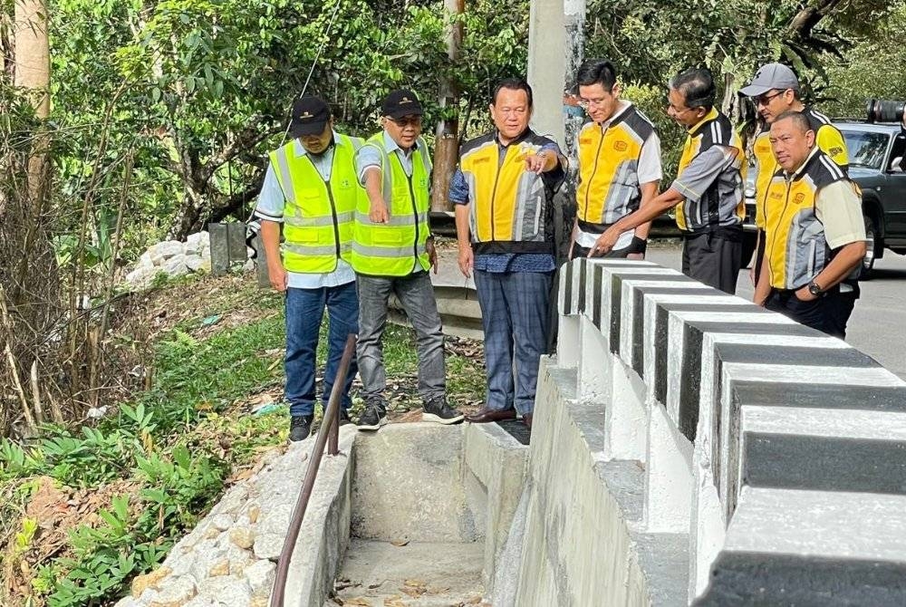 Alexander (tiga dari kiri) diberi taklimat berkenaan kerja pembaikan cerun yang runtuh dalam lawatannya pada Ahad.