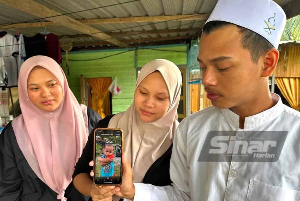 Che Muhamad Fahmi (kanan) bersama ahli keluarga yang lain melihat gambar Che Muhammad Faqih.