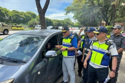 Lokman (depan) melakukan pemeriksaan terhadap sebuah kenderaan di tempat parkir di Tanjung Lipat Likas, Kota Kinabalu.