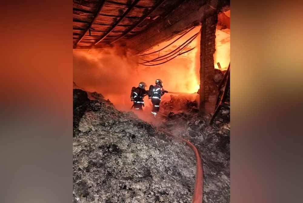 Anggota bomba sedang melakukan kerja-kerja memadamkan api dalam insiden kebakaran gudang kilang kopi di Cheng, Melaka pada malam Ahad.
