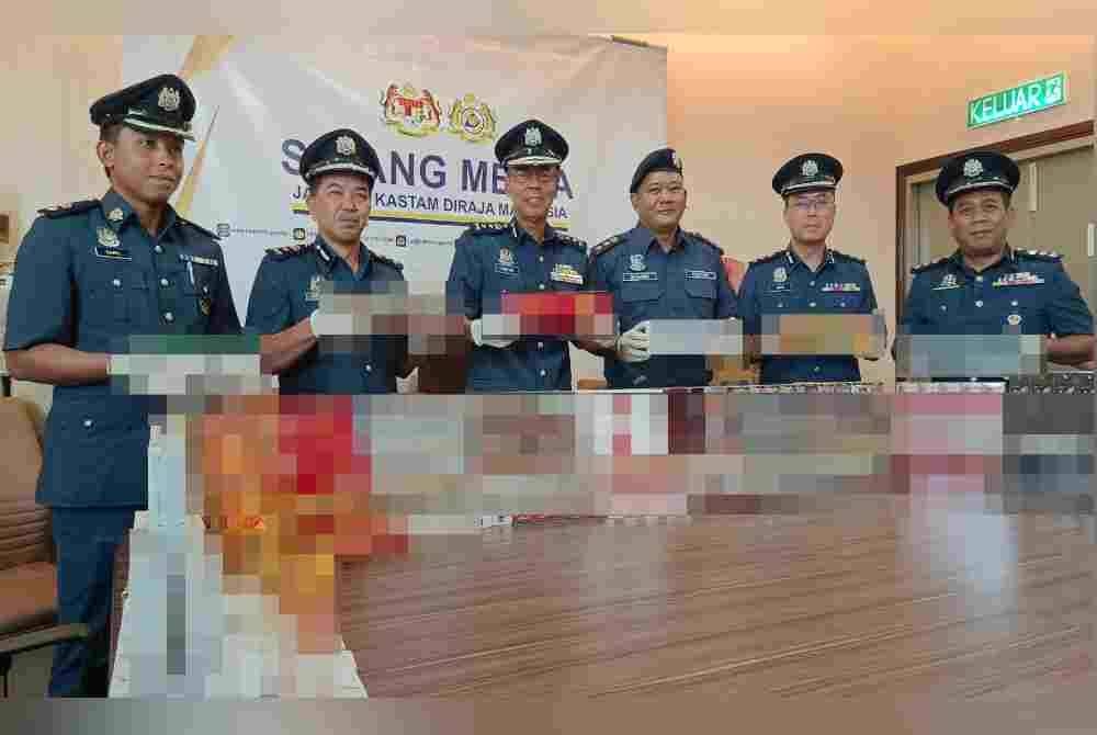 
Abdul Ghafar (tiga dari kiri) menunjukkan rokok-rokok bernilai RM2.1 juta yang dirampas dalam dua serbuan berasingan di daerah Manjung minggu lalu.