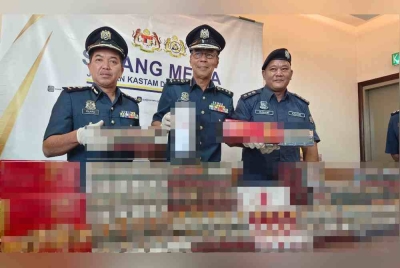 
Abdul Ghafar (tengah) menunjukkan rokok kretek dan rokok putih seludup yang dirampas dalam serbuan dua rumah tidak berpenghuni di Sitiawan dan Pantai Remis, minggu lalu.