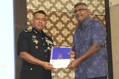 Kamarul Zaman (kiri) menyampaikan sijil penghargaan kepada anggota polis yang bersara pada majlis Meraikan Bakal Pesara dan Pesara Polis Kontinjen Johor di IPK, Johor Bahru, pada Isnin.