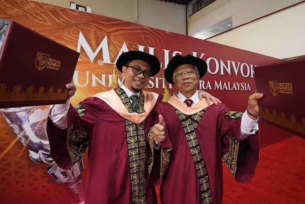 Lebih manis Md Damiri berkongsi detik bersejarah bergraduasi bersama anaknya, Mohamad Hazrol (kiri) yang turut menggenggam PhD daripada universiti sama pada Isnin. - Foto: FB UPM