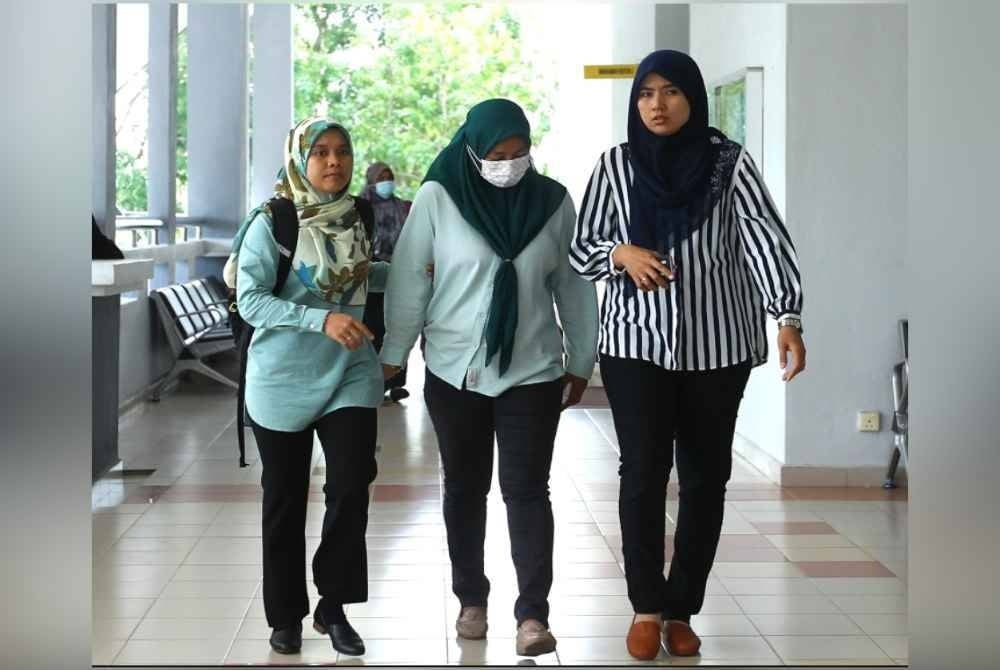 Norihan (tengah) diiring pegawai SPRM ketika hadir ke mahkamah