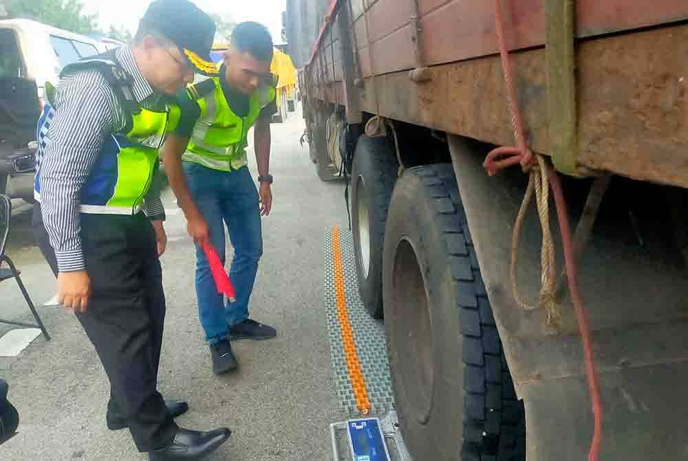 Azrin (kanan) melihat sebuah lori menjalani ujian timbangan berat semasa Ops Patuh Bersepadu JPJ dan JSPT di Plaza Tol Bandar Gamuda Cove pada Selasa.