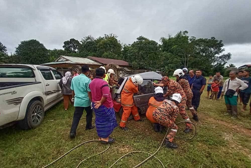 Anggota bomba berusaha mengeluarkan mangsa yang tersepit. Foto: Ihsan polis