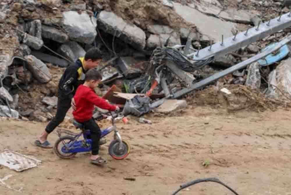 Kanak-kanak warga Palestin bermain berdekatan runtuhan bangunan di Jebaliya. - Foto AP