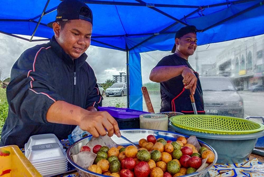 Arash (kiri) bersama pekerja menyediakan sebahagian kuih Cek Mek Molek 'Dragon Ball' yang dijual ketika ditemui Bernama di Pasir Tumboh di sini. - Foto Bernama
