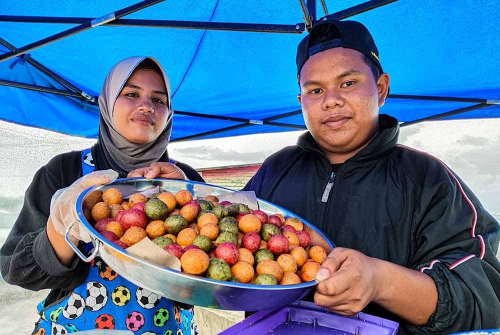 Arash (kanan) bersama pekerja menunjukkan kuih Cek Mek Molek yang diberi nama 'Dragon Ball' yang dijual ketika ditemui Bernama di Pasir Tumboh di sini. - Foto Bernama
