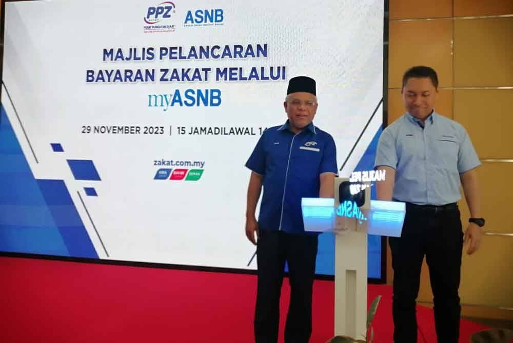 Abdul Hakim (kiri) bersama Muzzaffar menyempurnakan gimik pelancaran Bayaran Zakat Melalui myASNB di Wisma PPZ-MAIWP pada Rabu.