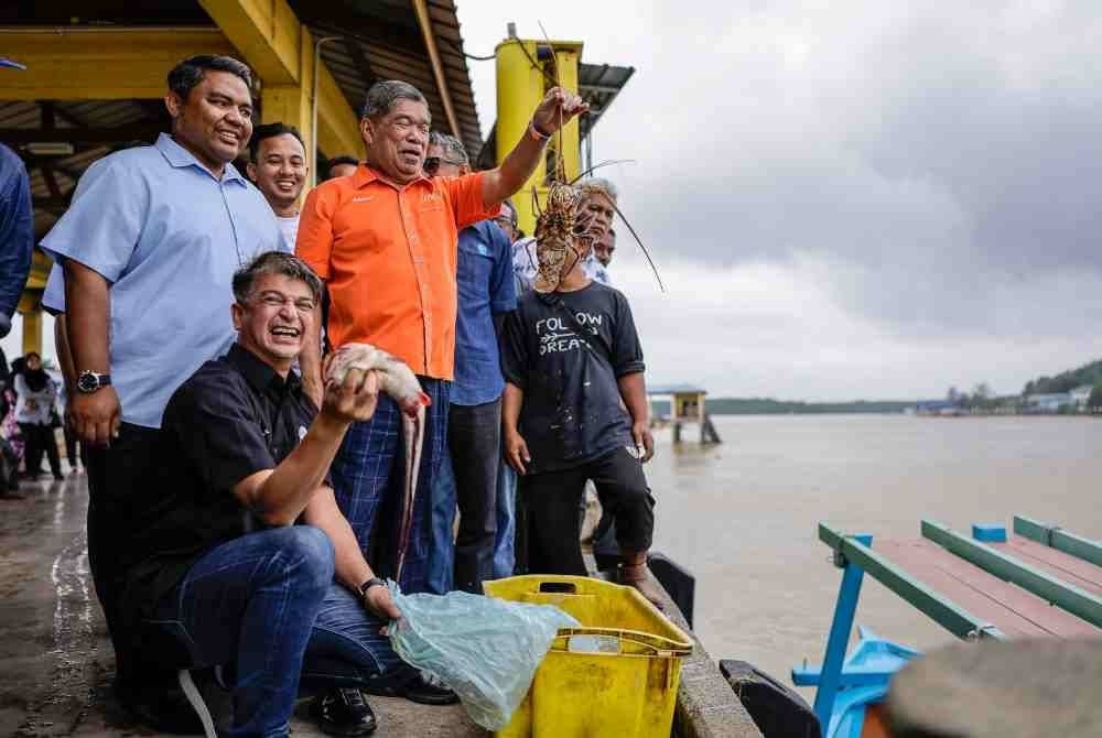 Mohamad (tiga dari kiri) gembira melihat hasil tangkapan nelayan ketika beliau melakukan lawatan di jeti pendaratan Kompleks PerikananLKIM sempena Program Santai Madani Bersama Nelayan hari ini. - Foto Bernama