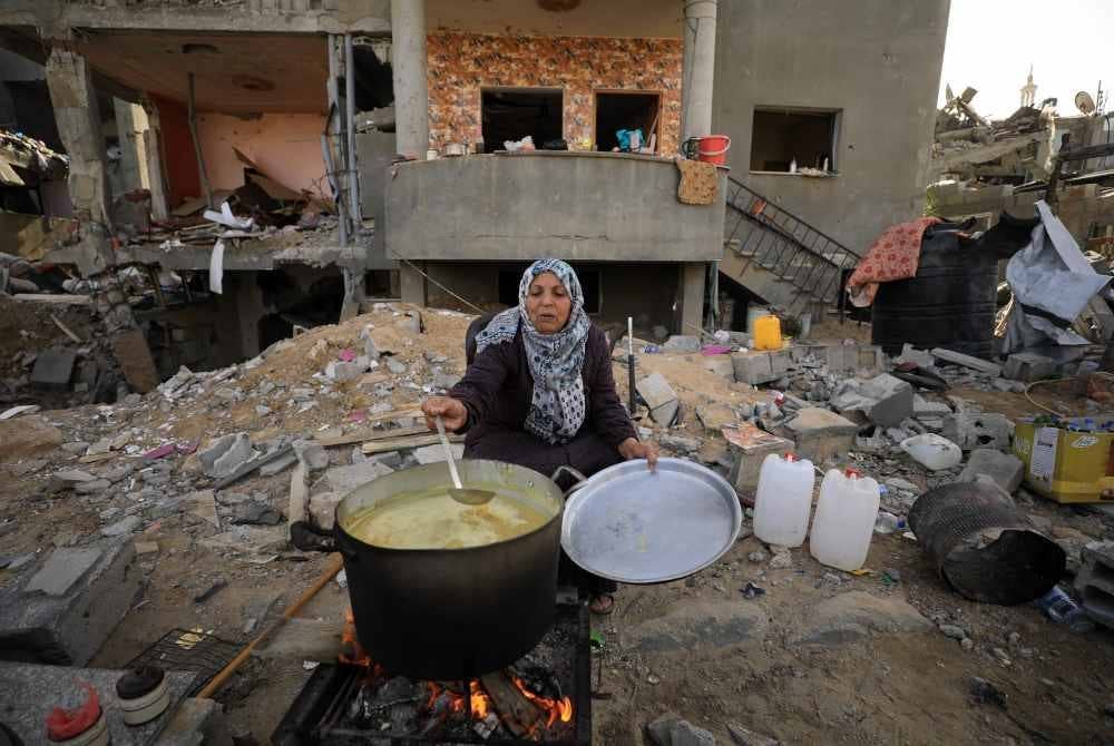 Seorang warga Palestin memasak di bandar Khan Younis, selatan Genting Gaza. - Foto Xinhua