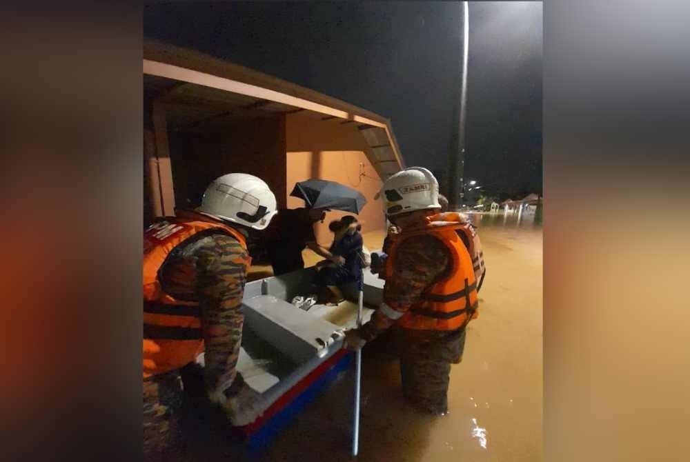 Anggota bomba membawa mangsa banjir dari taman Bunga Ros dengan menggunakan bot. - Foto BBP Kempas