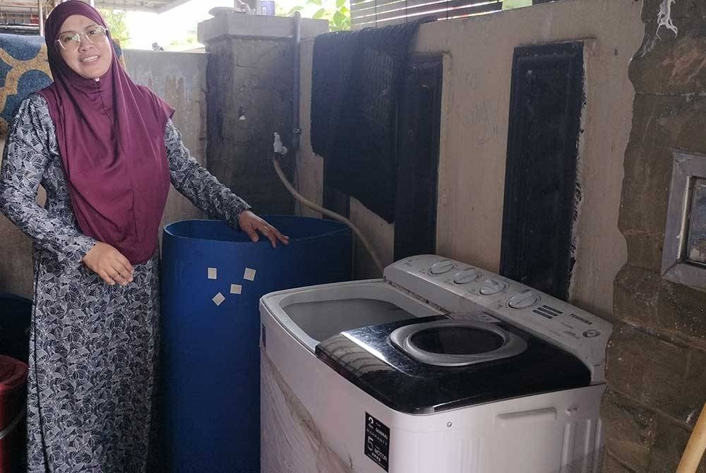 Siti Hajar mengambil keputusan menempatkan tong air dan mesin basuh di luar rumah disebabkan bekalan yang sering terganggu.