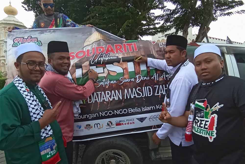 Humaidi (dua,kiri) dan Muhammad Najib (dua, kanan) menandatangani kain rentang sebagai tanda sokongan kepada Palestin.