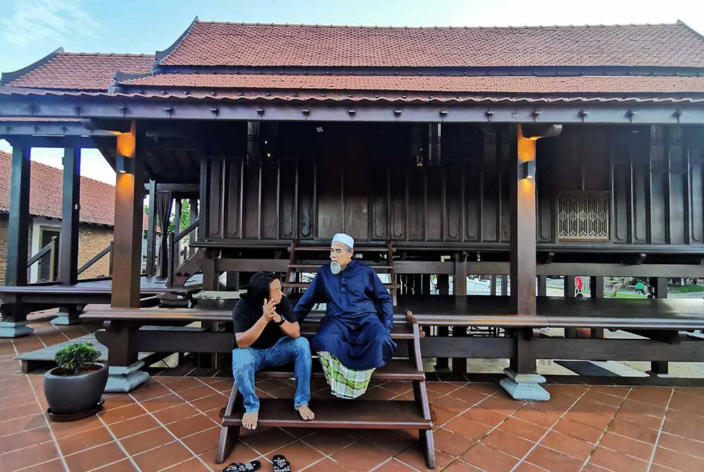 Wan Mohd Azam (kanan) dan Sollah berbual di tangga surau yang terletak di Kampung Losong Masjid, di Kuala Terengganu.