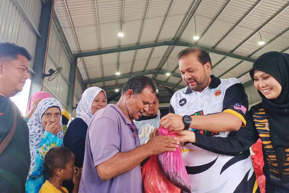 Iskandar Dzulkarnain dan isteri, Datin Faradila Abdul Khair menyerahkan sumbangan ikan dan sayur di Dewan Terbuka Kampung Senggang, Kuala Kangsar pada Sabtu.