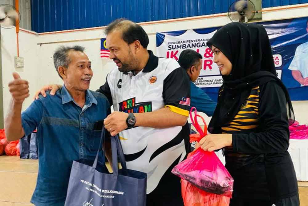 Iskandar Dzulkarnain (tengah) menyantuni penduduk yang hadir dalam program penyerahan sumbangan ikan dan sayur di Dewan Terbuka Kampung Senggang, Kuala Kangsar pada Sabtu.