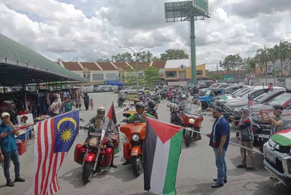 Rozi (kanan) dan Fauzi (kiri) melepaskan peserta konvoi motosikal kuasa besar dan pacuan empat roda dalam Program Jualan Amal Gaza di tapak parkir Pasar Raya Econsave Taman Teratai, Johor Bahru pada Sabtu.
