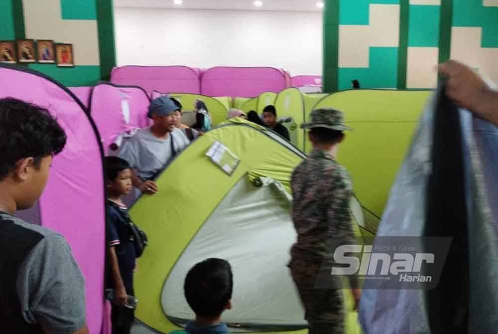Orang ramai membantu kerja-kerja membuka khemah sementara di PPS Dewan Muafakat Kampung Cahaya Baru.