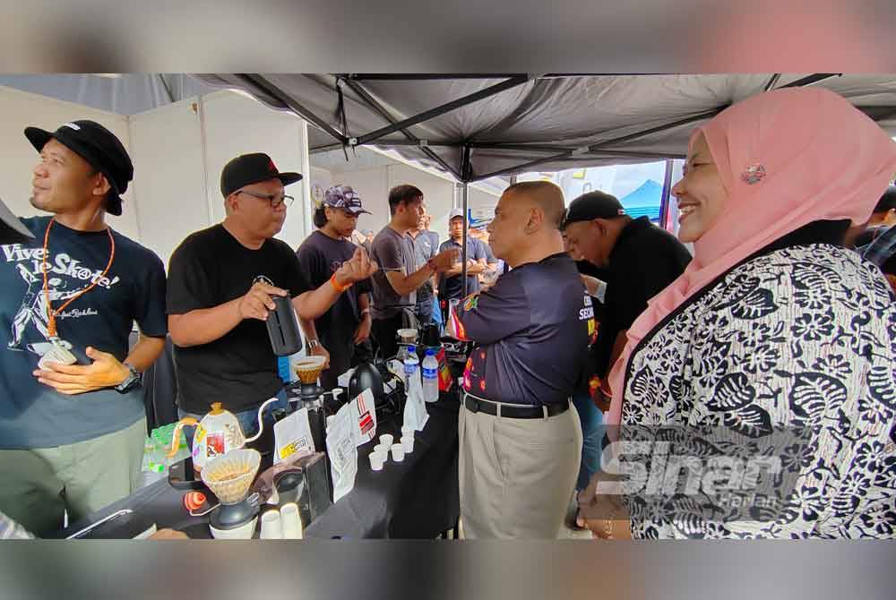 Saarani (tengah) bersama Salbiah melawat reruai yang menjual kopi pada Karnival Kopi Perak 'Cherita Secangkir Kopi' di Ipoh.